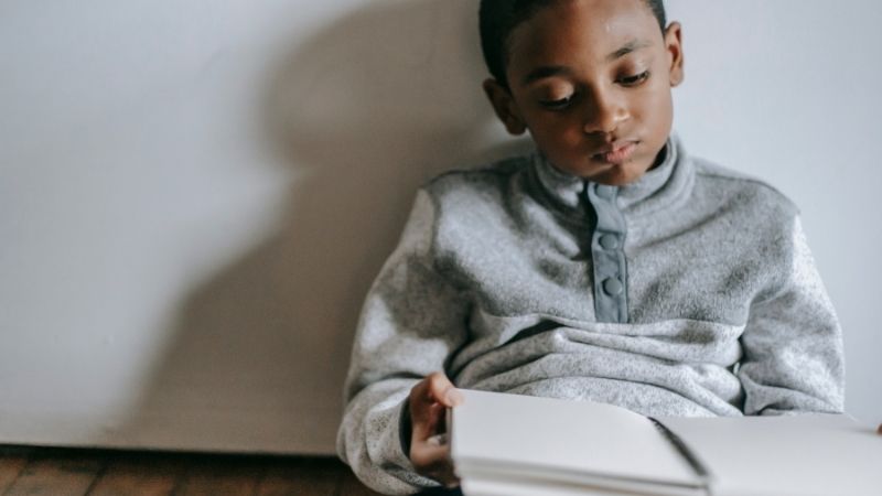 A black boy struggling to read