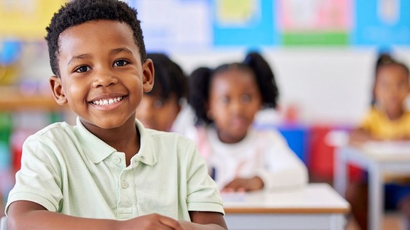 Black boy inside a classroom staring at camera